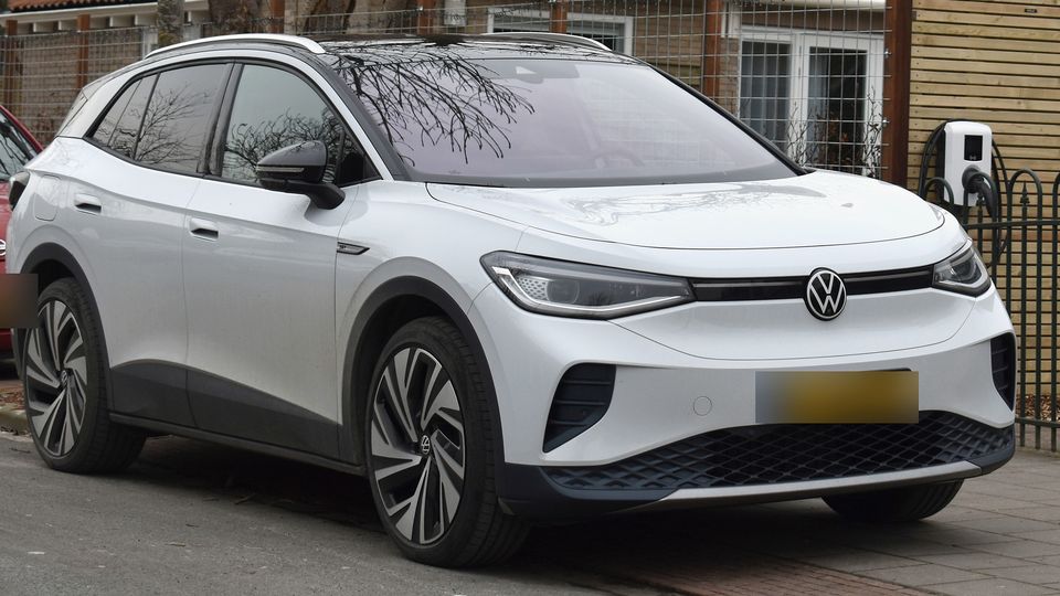Hvid VW ID.4 parkeret ved en ladestander foran et hus